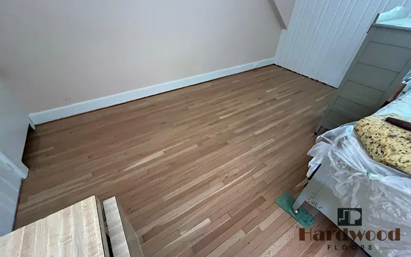 Freshly sanded natural oak strip hardwood floor in a bedroom under renovation by JP Hardwood Flooring.